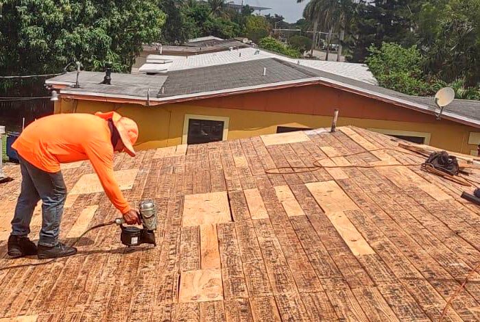 A roofer from Alom Builders carefully works on a roof, demonstrating his stability and safety.